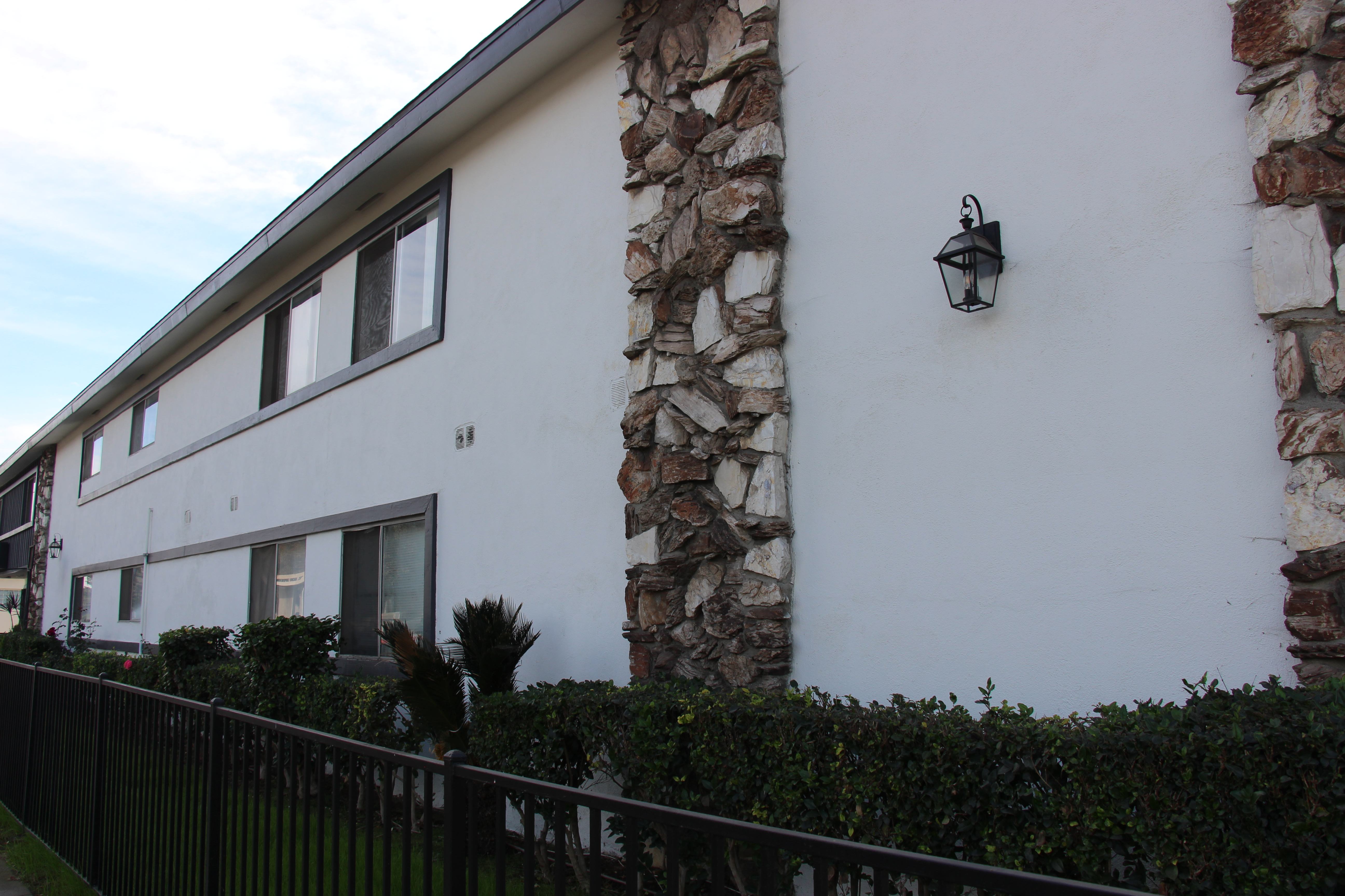 A white house with a stone pillar and a black fence.